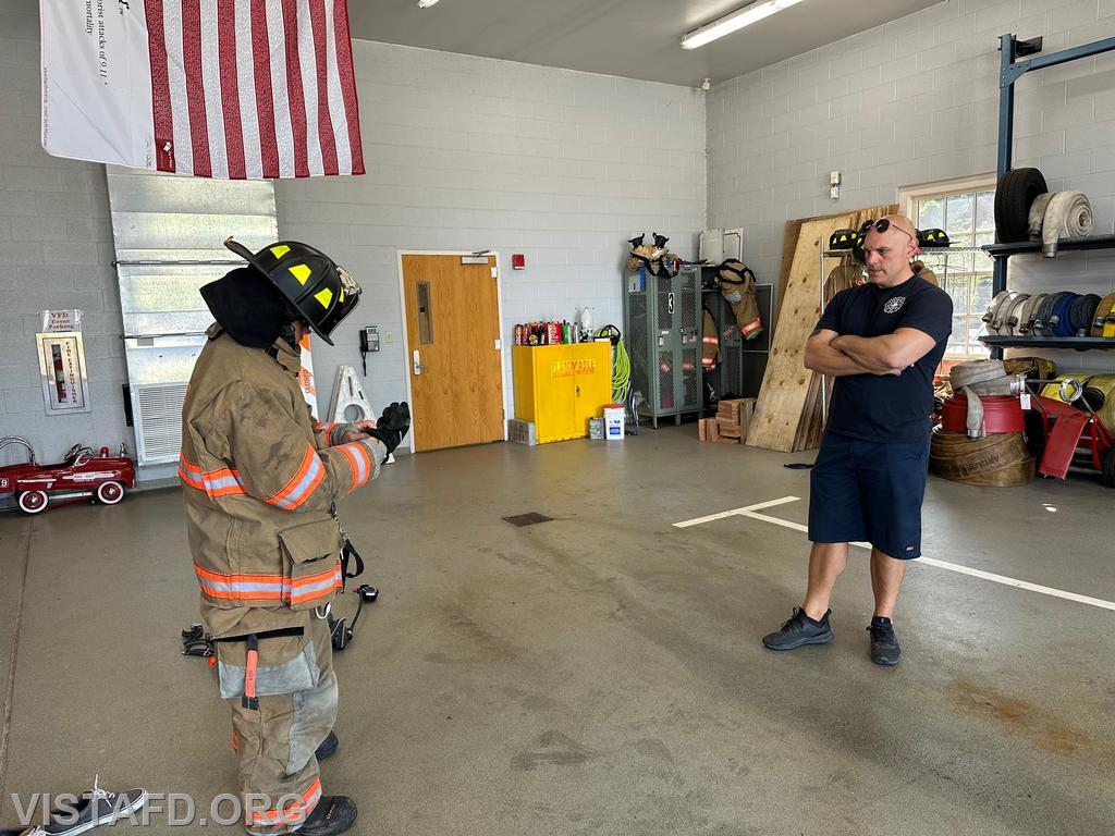Probationary Firefighter Teddy Goetz putting on firefighting gear as Captain Marc Baiocco looks on - 09/03/23