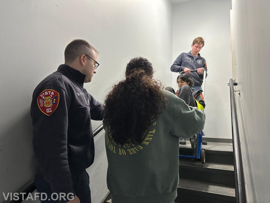 EMT Grant Vialardi and Probationary EMT Candidate Skyla Warren going over how to operate the stair chair as Assistant Chief Brian Porco looks on - 11/25/24