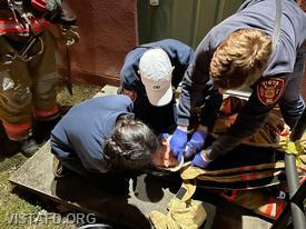 EMT Savannah Phillips, Firefighter/EMT Andy Korman, and EMT Grant Vialardi apply a collar to a downed firefighter during the "EMS Call Scenarios" drill